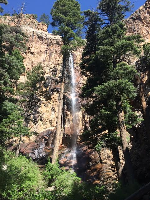First view of Apache falls, framed by tall Ponderosa pine trees